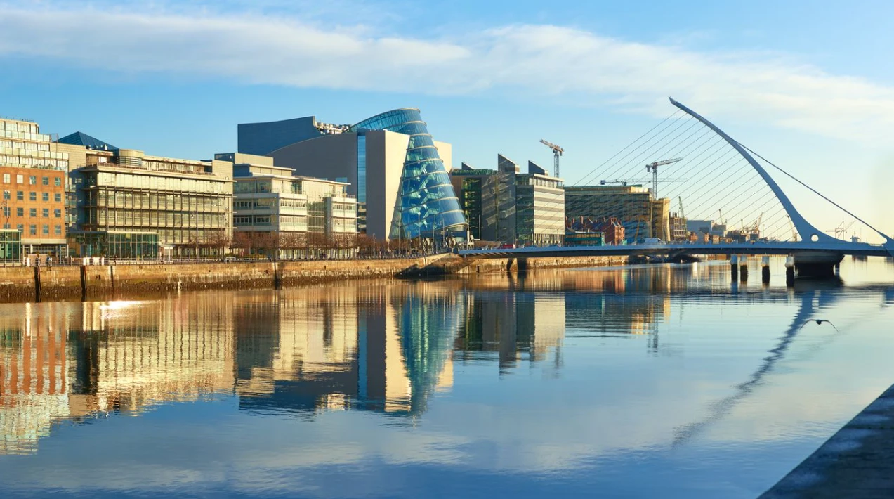 El río Liffey en Dublín, con el puente Samuel Beckett y edificios modernos reflejados en el agua